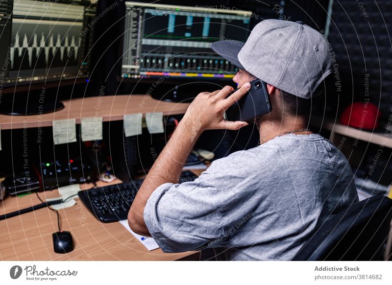 Male musician working in studio and speaking on cellphone record equipment man smartphone talk male device gadget connection professional mobile table