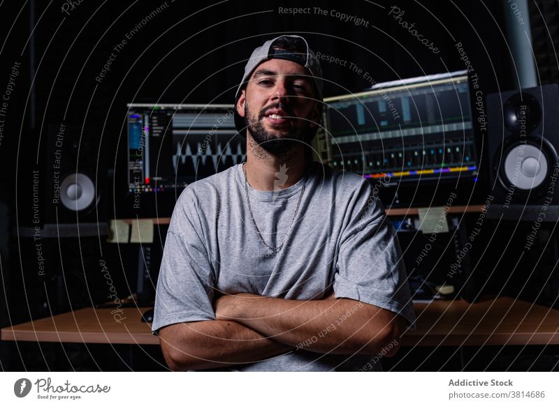 Confident man in dark recording studio music artist singer style musician monitor equipment male sound modern entertain trendy creative confident sit audio