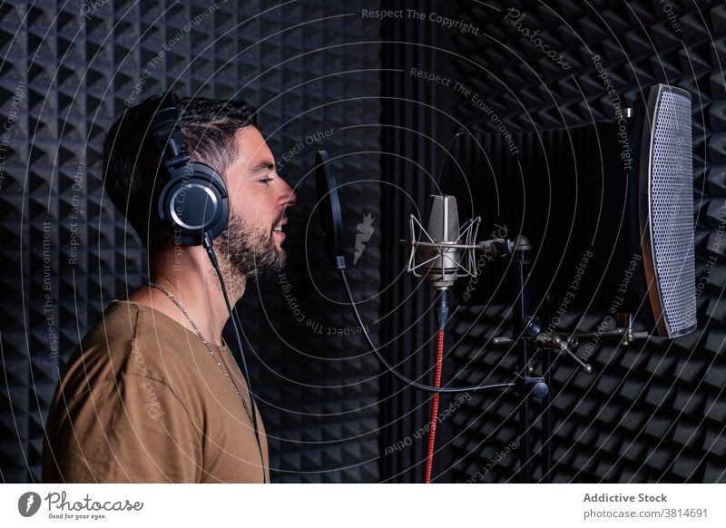 Man in recording studio microphone sing man artist singer headphones acoustic foam male sound proof song room music musician modern contemporary gadget listen