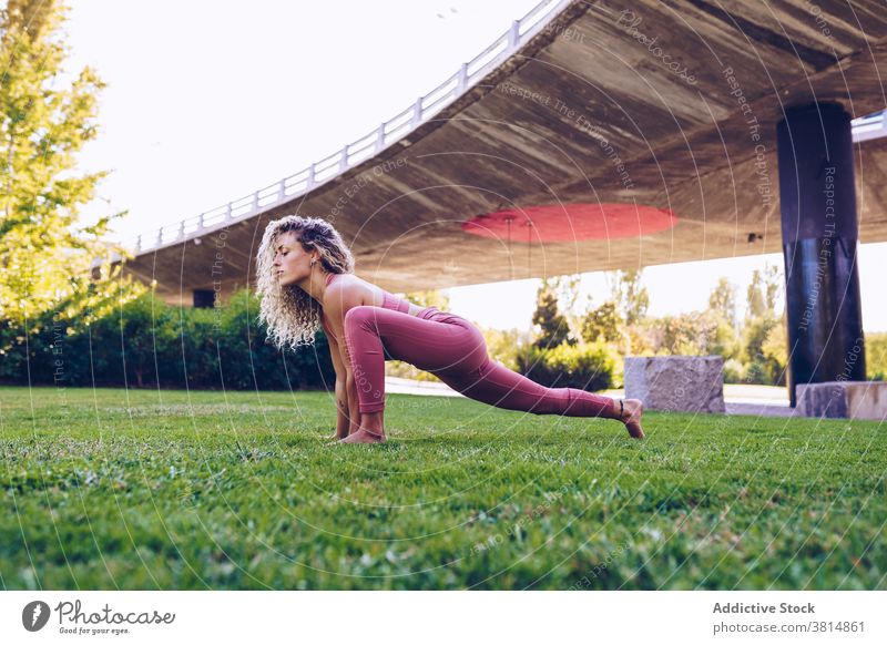 Focused woman practicing yoga in park asana flexible pose practice balance position slim female wellness harmony wellbeing activity concentrate vitality