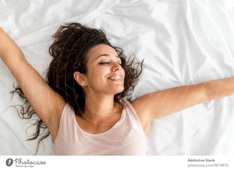 Cheerful woman waking up in morning wake up awake stretch bed lying delight sweet comfort female bedroom home relax rest cozy apartment peaceful pleasure joy
