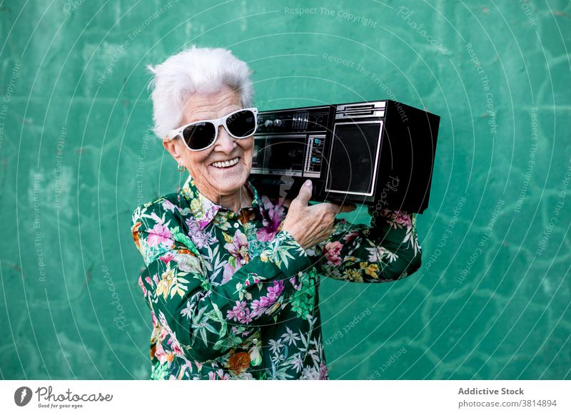 Senior woman with record player standing near wall senior music style elderly listen sound active female trendy lifestyle urban aged old device audio vintage