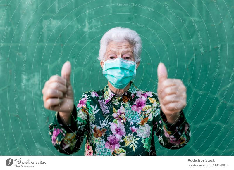 Senior woman in medical mask showing thumbs up senior coronavirus thumb up optimist positive protect gesture covid 19 covid19 pandemic elderly sign female