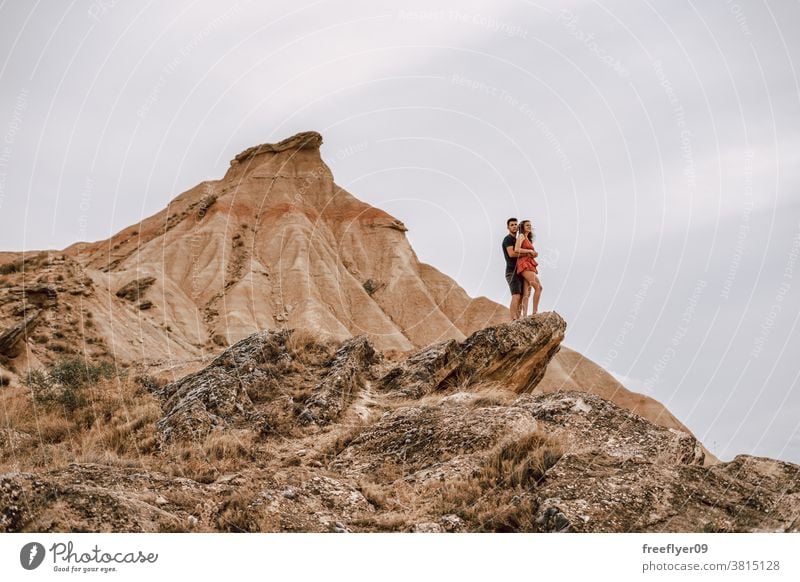 Couple on top of a rock on a desertic landscape couple honeymoon adventure romantic heterosexual freedom sightseeing walking tourists sports clothing young 20s
