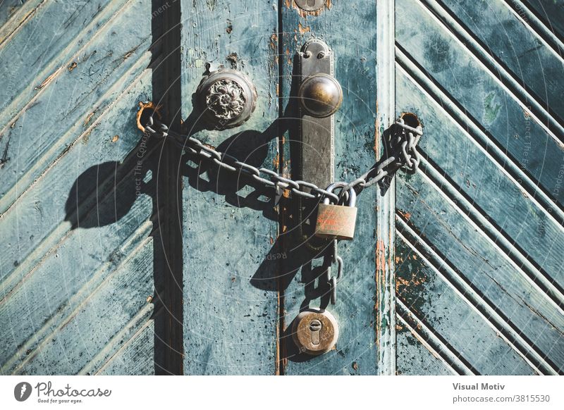 Knob and padlock on a weathered blue wooden door of an old factory knob front architecture detail abstract exterior urban antique aged background chipped chain