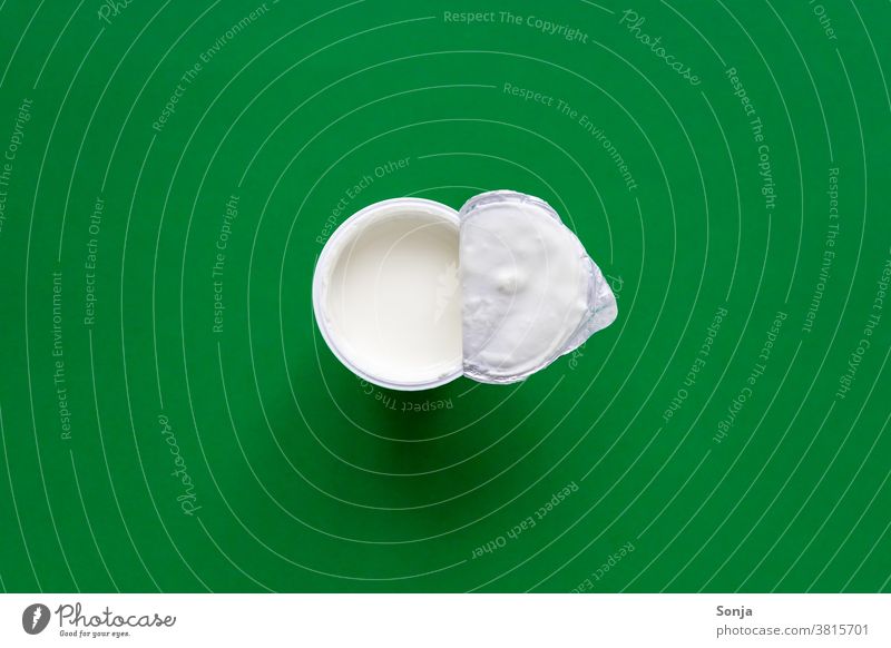 An opened plastic cup with yoghurt on a green background. Top view. Yoghurt Plastic cup Open plan Food Nutrition Diet Healthy Fresh Breakfast Vegetarian diet