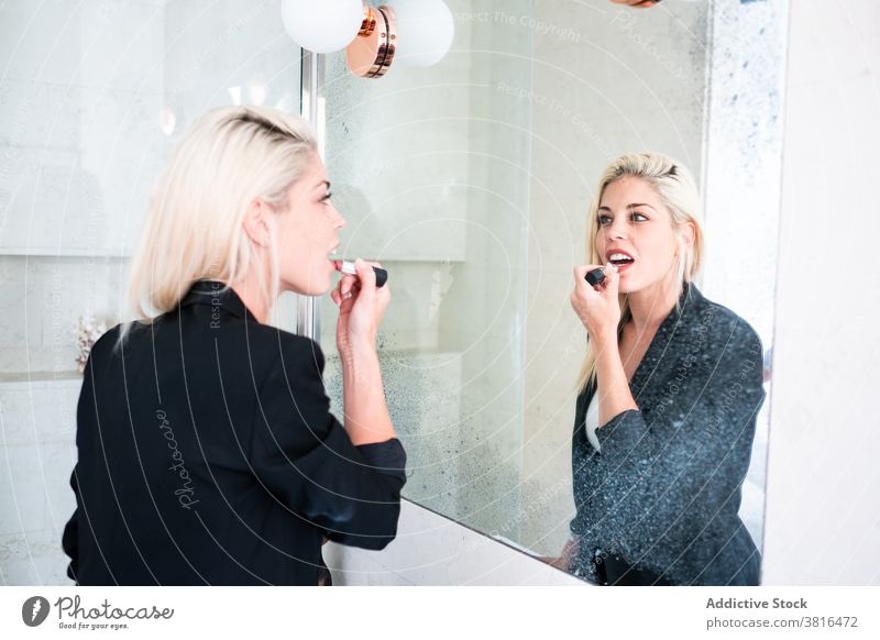 Blonde woman applying lipstick near mirror makeup morning routine reflection cosmetic beauty young female paint bathroom skin care daily treat lifestyle lady