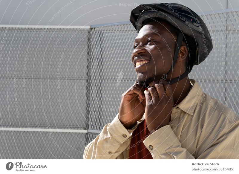 Smiling man with helmet on street city put on ready ride protect cheerful male ethnic black african american transport contemporary casual safety vehicle smile