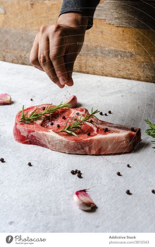 Crop cook adding seasoning on t bone steak beef raw chef condiment sprinkle appetizing delicious cuisine meat meal food tasty recipe gourmet culinary fresh