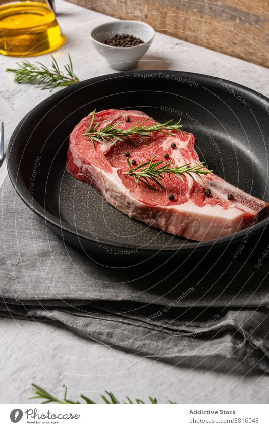 Raw beef steak on pan in kitchen bone t bone rosemary meat delicious uncooked pepper pea raw table fresh dish gourmet food spice herb tasty dinner recipe