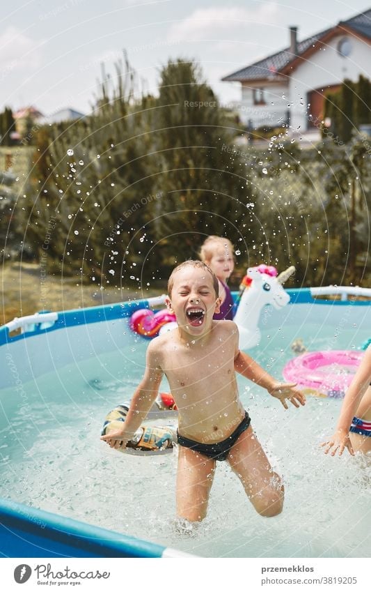 Boy jumping and splashing in a pool authentic backyard childhood children family fun garden happiness happy joy kid laughing lifestyle playful playing real