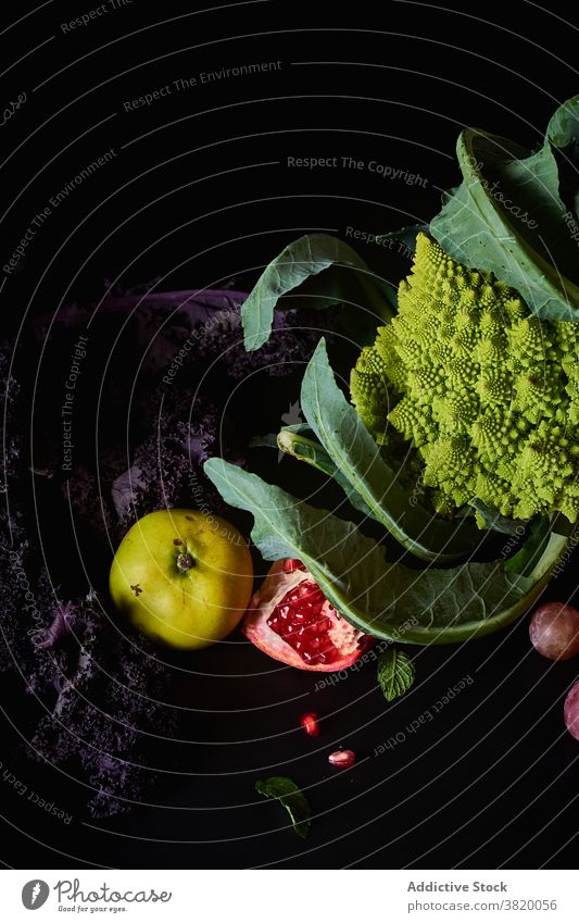 Still life with various vegetarian meal ingredients black food still life composition art produce organic dark food cabbage romanesco grapes muscatel pink kale