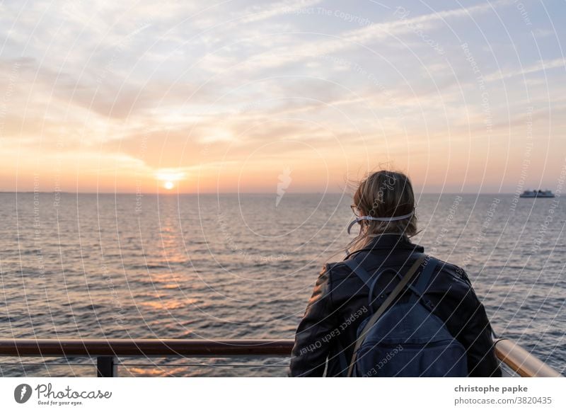 Woman with mouth-nose-protection looks at the sea mouth-nose protection travel Mask pandemic Ocean Sunset corona Risk of infection Corona virus COVID covid-19