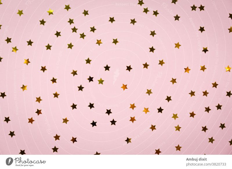 Save Download Preview Golden star sprinkles on pink. Festive holiday background. Celebration concept. Top view, flat lay. Horizontal christmas party glitter