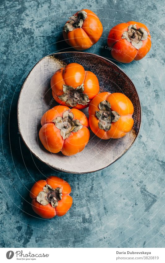 Delicious persimmon in a plate on a blue background sweet fresh juicy healthy orange food organic diet ripe vegetarian fruit nutrition delicious natural tasty