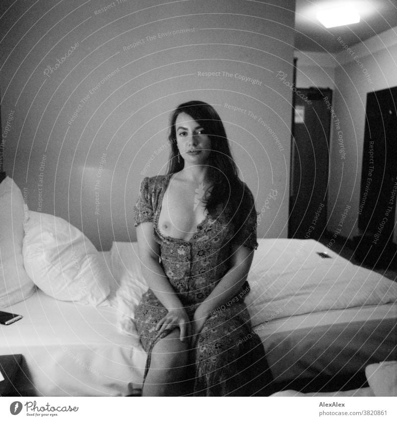 Portrait of a young woman sitting on a hotel bed Classic Wild Summer dress Dress décolleté Youth (Young adults) Room room Looking into the camera long hairs