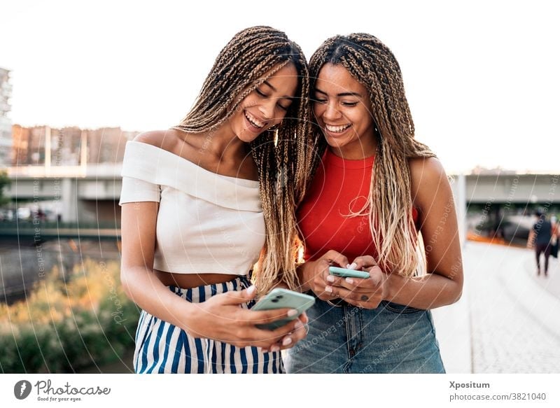 Happy Sisters Using Phone using phone typing smiling front view sisters african american braids street attractive young style expression beautiful pretty ethnic