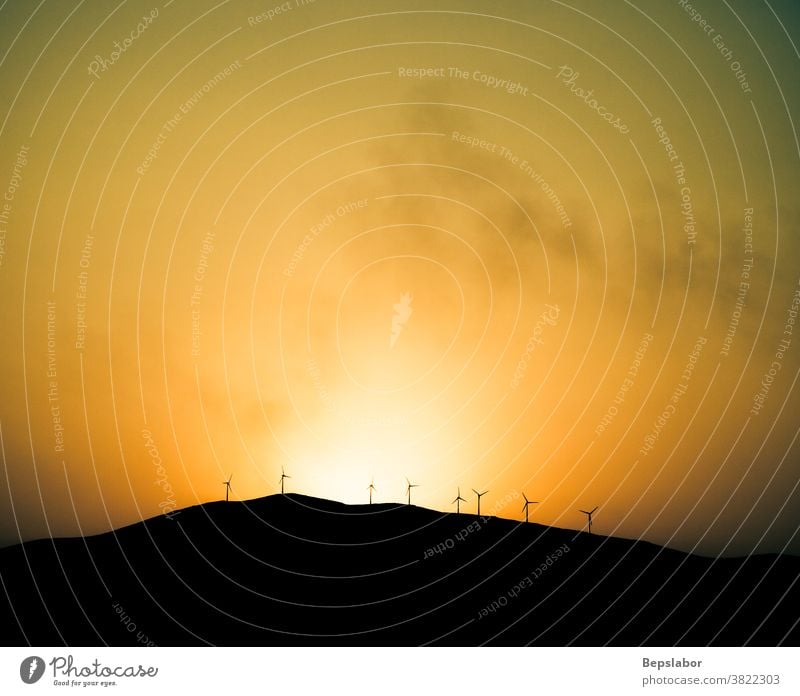 Windmills Turbines Propellers Energy on the hill at sunset with an orange sky background clouds energy landscapes light majestic mountain nature night panorama