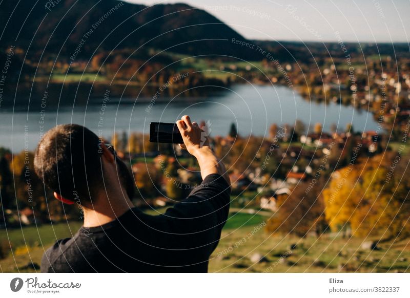 A man takes a picture with his mobile phone of Schliersee in the sunshine schliersee Landscape photo Cellphone Lake smartphone Man Take a photo Trip Autumn