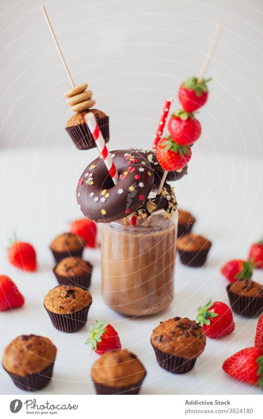 Chocolate milkshake served with sweet pastry and strawberry dessert candy donut muffin various assorted colorful chocolate glass food yummy sugar beverage drink