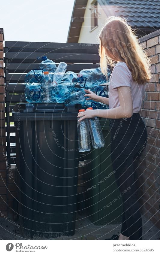 Young woman throwing out empty used plastic water bottles into trash bin blue collect collecting container crushed disposal ecology environment female garbage