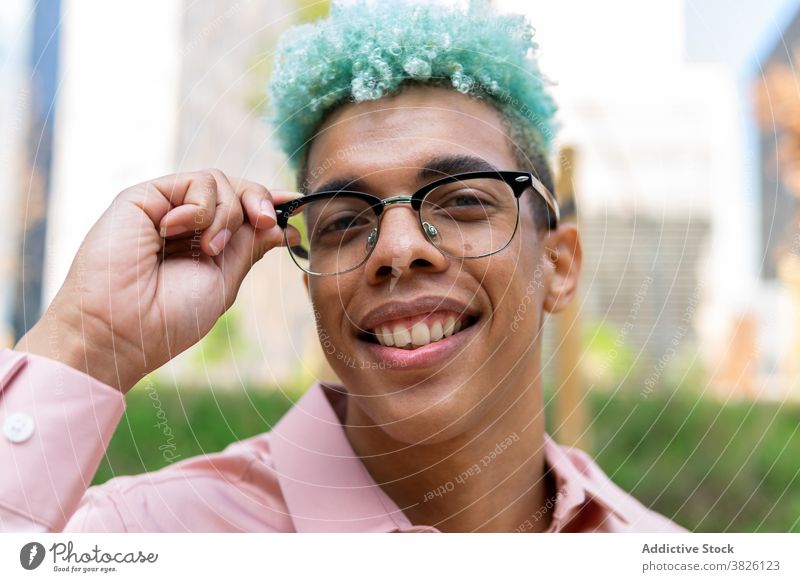 Smiling ethnic man with Afro hairstyle and in glasses in city blue hair afro handsome appearance eyeglasses trendy generation male black african american