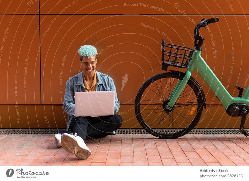 Ethnic informal male freelancer working in city hipster man remote speak using laptop blue hair ethnic black african american connection smile gadget device