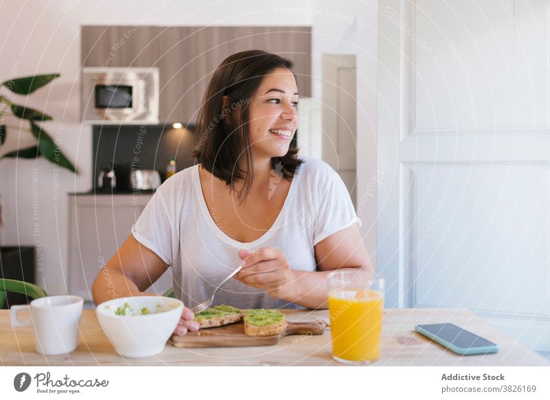 Smiley woman looking at the window while she's having breakfast indoors home house girl avocado shopping kitchen coffee morning caucasian brunette table
