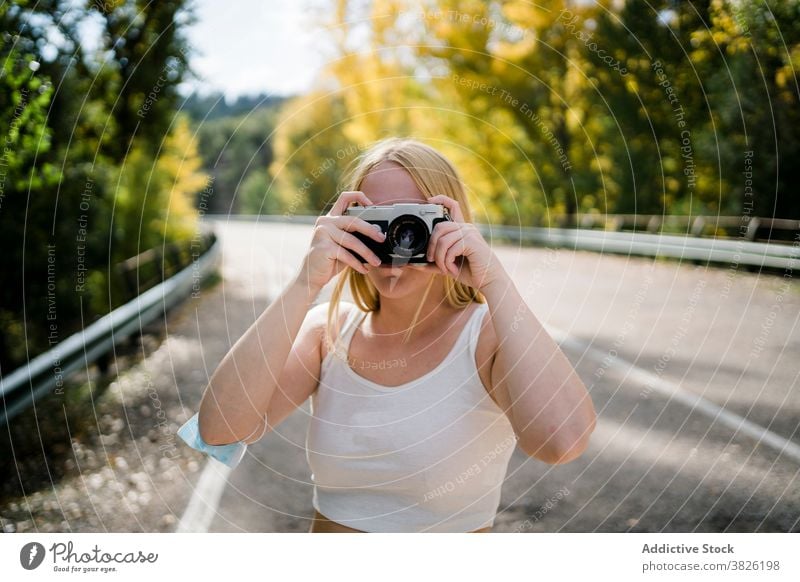 Woman with photo camera standing on road in autumn countryside woman take photo forest photography nature female photographer roadway journey travel fall