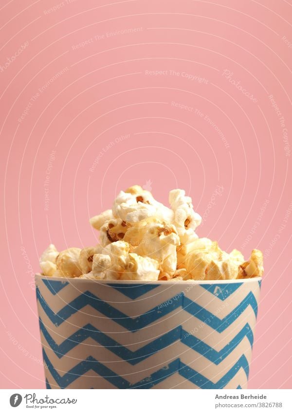 Fresh popcorn on a pink background appetizer box bucket cinema classic closeup color colorful container copy space crunchy cup delicious entertainment fast food