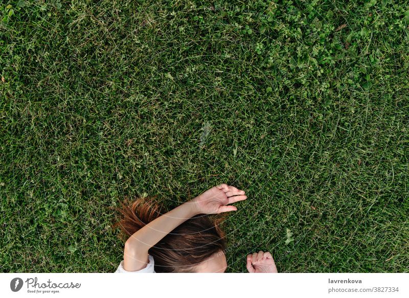 Faceless shot of woman lying on green grass girl female lifestyle adult person outdoors park happy top view above faceless hands summer seasonal relaxed