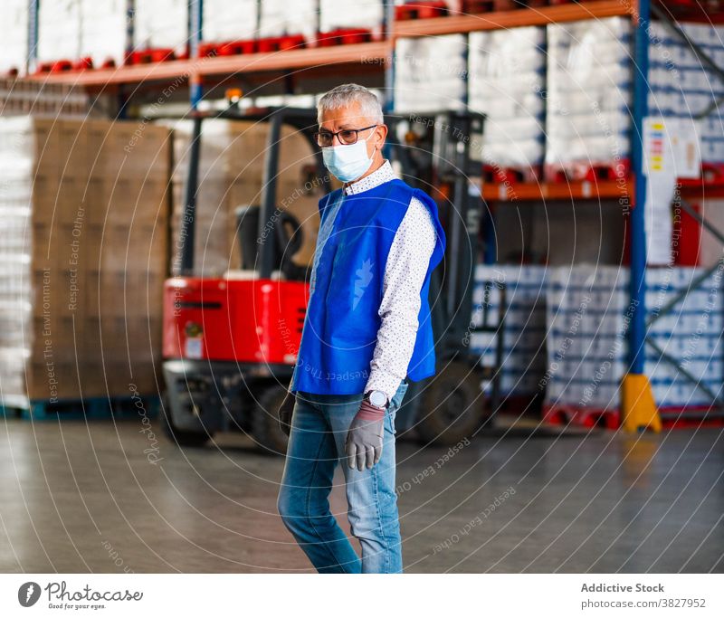 Calm male worker standing in warehouse man professional at work industry uniform calm focus storehouse industrial coronavirus adult vest serious employee