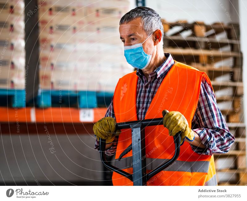 Concentrated adult worker using dolly cart working in warehouse man trolley employee focus concentrate move supply handle serious storage specialist