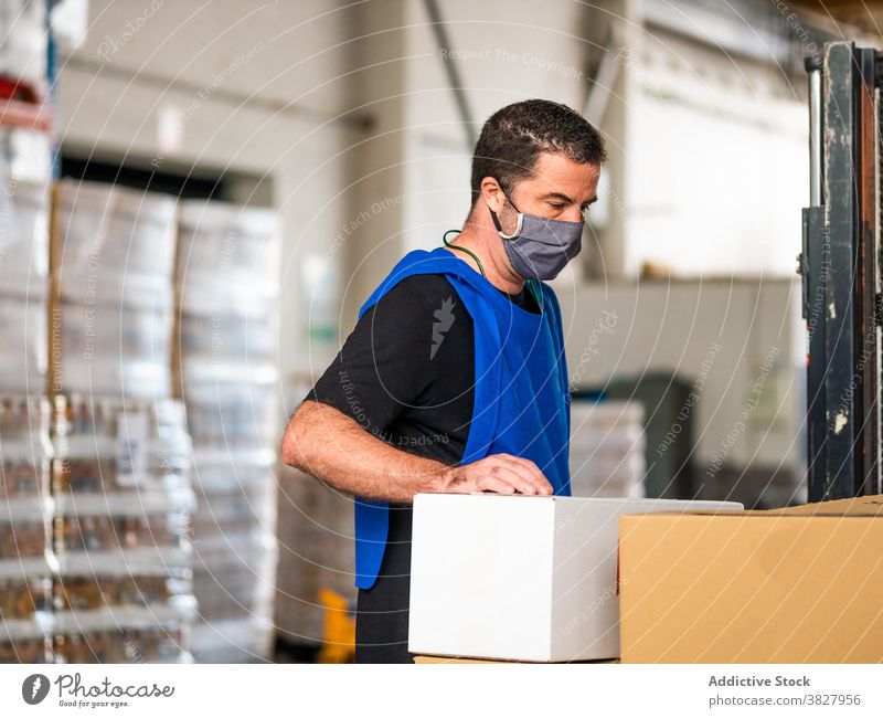 Serious warehouse worker standing near big carton boxes man container package delivery man workplace parcel busy storage specialist professional wrap at work