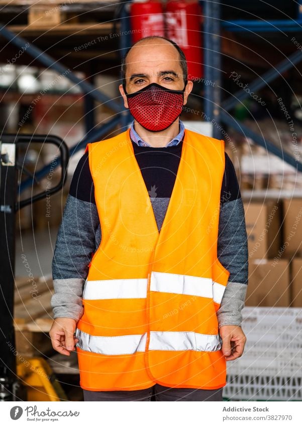 Male warehouse employee in uniform standing near rack in warehouse man worker professional at work storage storehouse workplace industry calm focus industrial