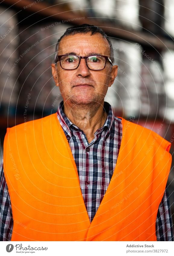 Male warehouse employee in uniform standing near rack in warehouse man worker professional at work storage storehouse workplace industry calm focus industrial
