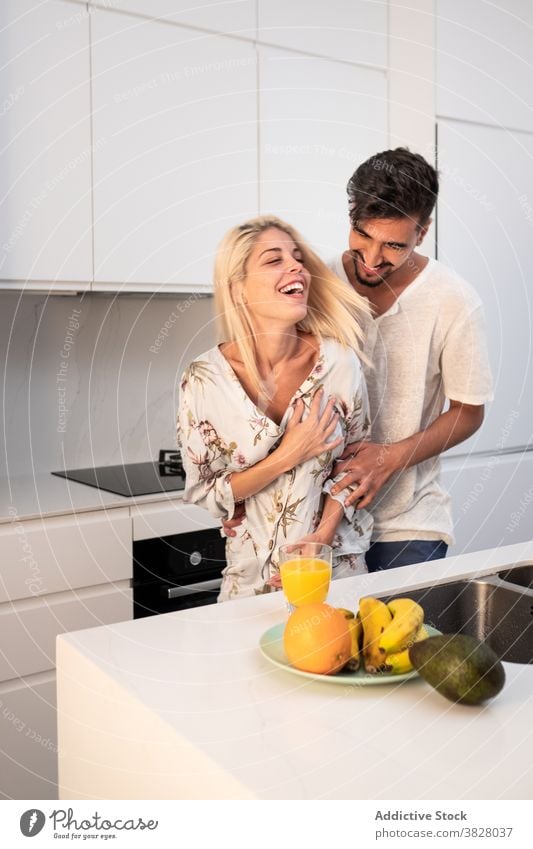 Cheerful couple hugging tenderly in kitchen embrace love together morning home domestic girlfriend boyfriend modern relationship fondness close cheerful