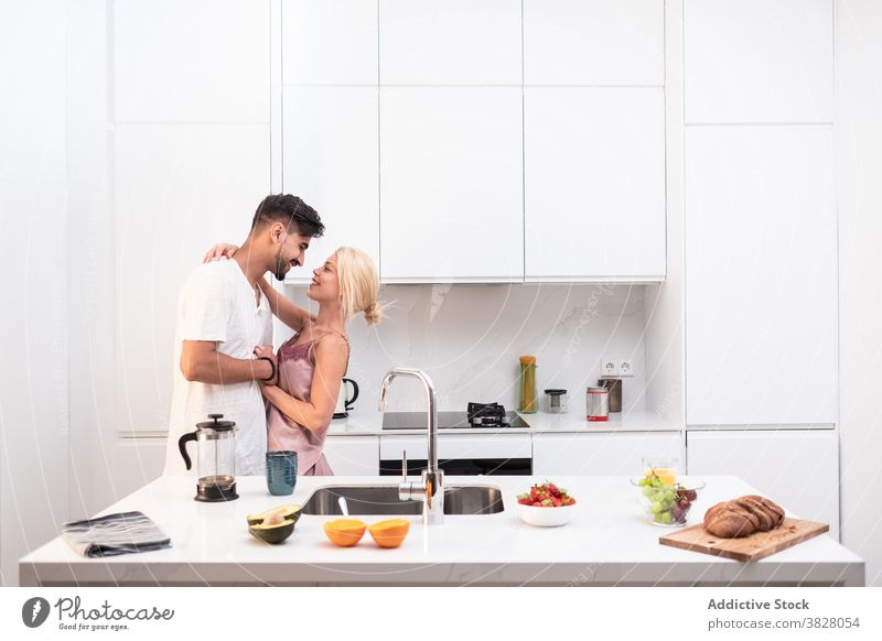 Cheerful couple hugging in kitchen at home breakfast together morning domestic love delight relationship affection romantic girlfriend embrace boyfriend joy