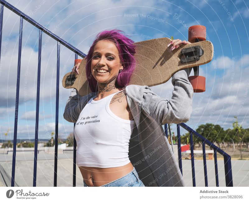 Determined woman with longboard in city millennial independent informal young pink hair fancy skater confident female modern hipster fashion trendy style