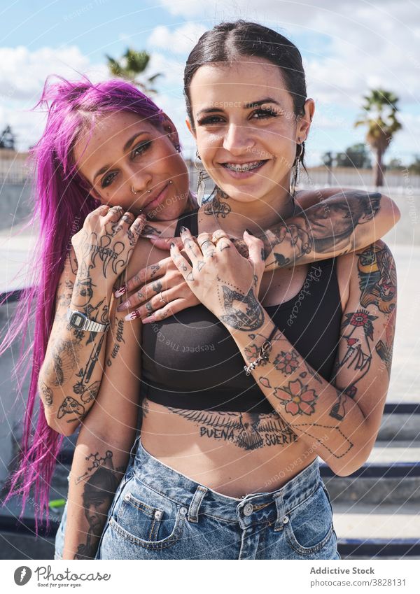Cheerful informal women hugging in city pink hair friend millennial hipster together tattoo appearance urban street eccentric friendship content bonding smile
