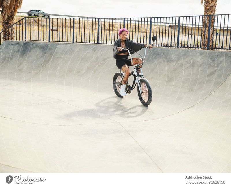 Happy woman on bike in skate park bmx confident bicycle extreme tattoo style outfit sit trendy urban young cool transport freedom summer city cyclist hobby