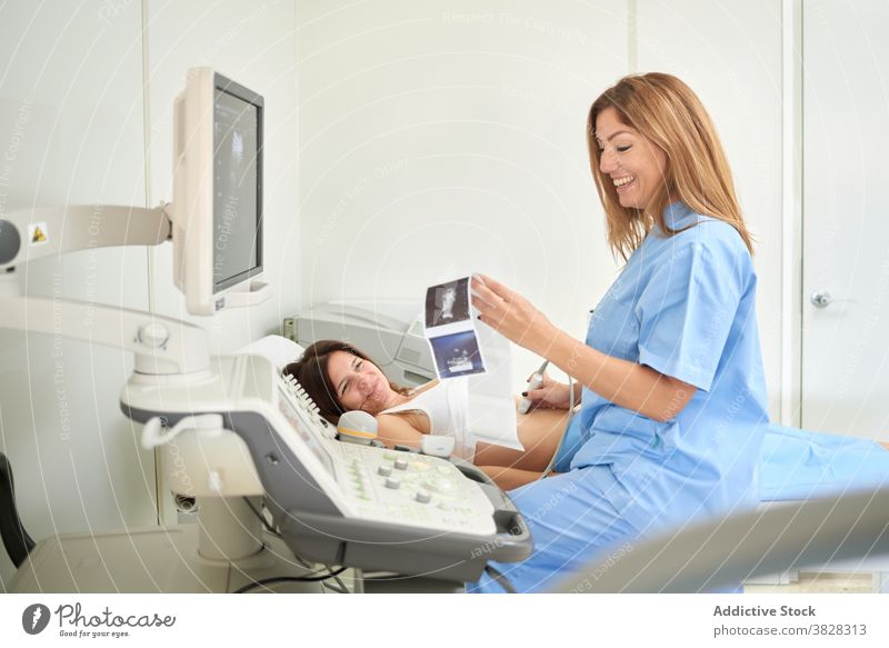 Doctor watching ultrasound images near scanner and unrecognizable patient doctor sonography diagnostic machine check uniform clinic women technician diagnose
