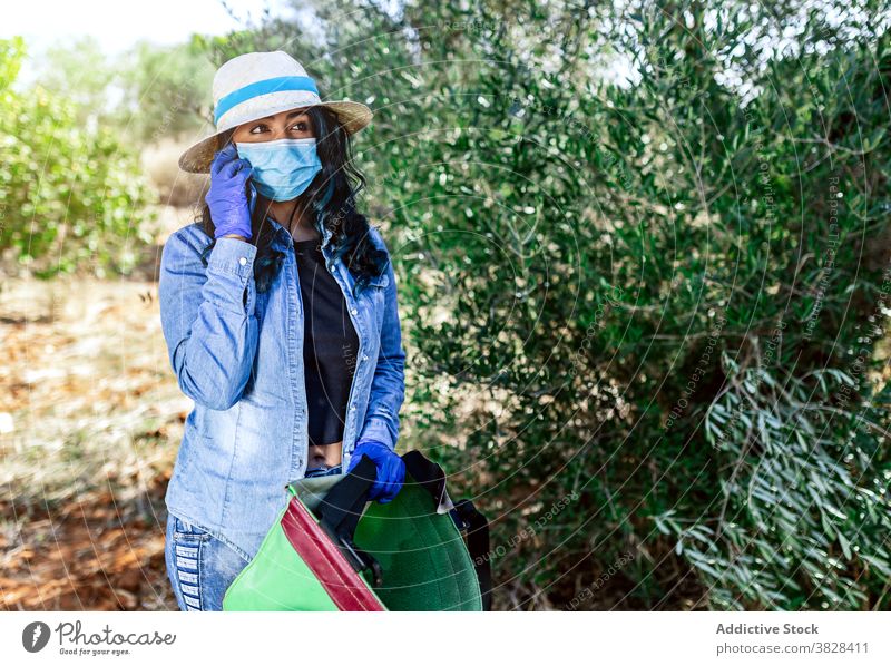 Young woman in medical mask talking on smartphone during harvest phone call covid conversation using garden protect agriculture female covid19 covid 19