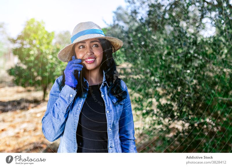 Young woman talking on phone while standing in garden using positive work orchard harvest fruit farm female connection communication digital professional glad