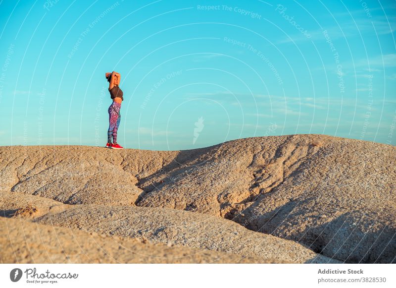 Sporty woman standing on dry rocky terrain freedom sporty outstretch desert rough badlands alone nature enjoy meditate adventure hill drought activity energy