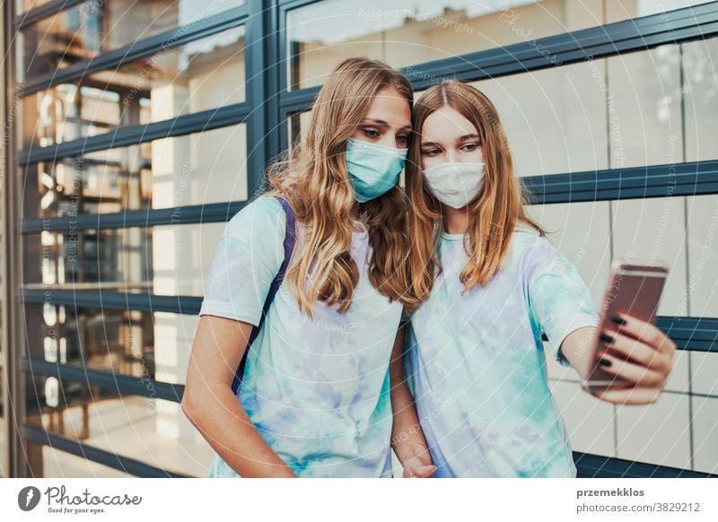 Young women girls taking selfie wearing face masks to avoid virus infection caucasian cellphone conversation covid-19 female lifestyle mobile outbreak outdoors