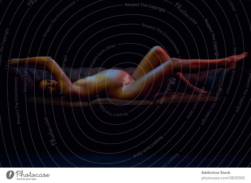 Sensual pregnant woman lying on sofa in darkness belly erotic motherhood anticipate expect hot sexy naked female tummy nude parenthood fertile birth abdomen