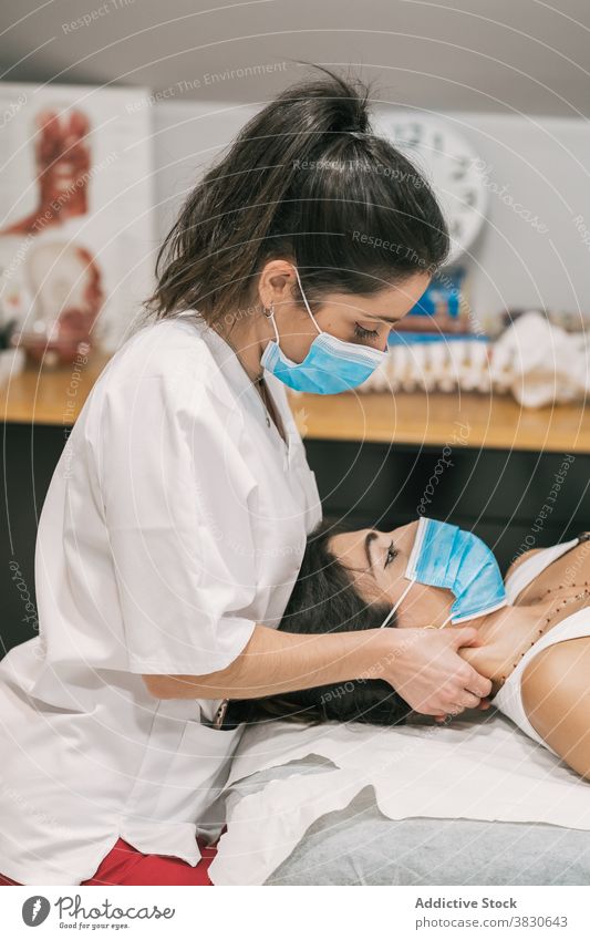 Therapist massaging neck of female patient in mask physiotherapy therapist massage doctor clinic treat professional healthy health care medicine specialist