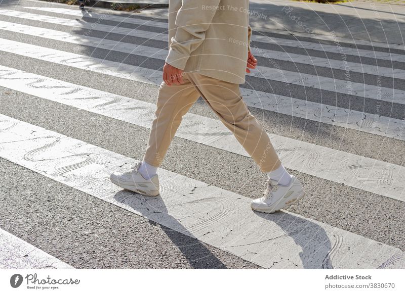 Unrecognizable man walking on roadside on crossing pedestrian crosswalk crossroad commute street traffic town asphalt urban casual outfit sunny stand pavement