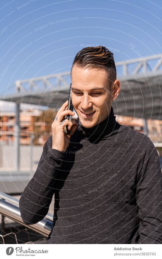 Young man having phone call on smartphone using communicate smile speak work positive male discuss remote busy job talk gadget device casual trendy glad listen